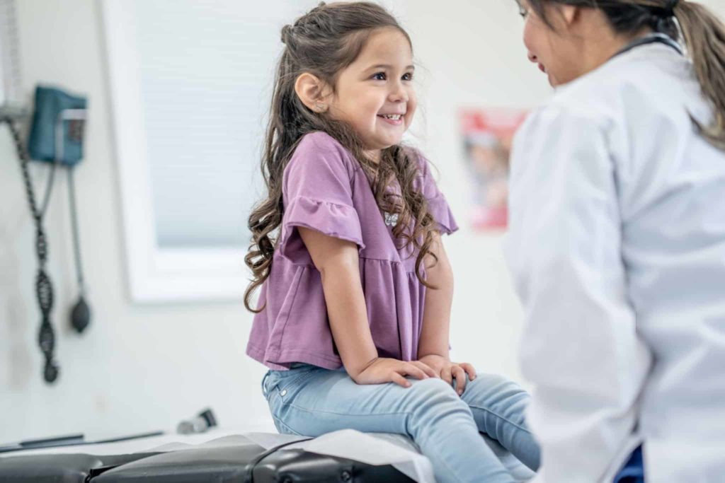 Enfant souriant au pédiatre et neuropédiatre dans une consultation de pédiatrie et neuropédiatrie